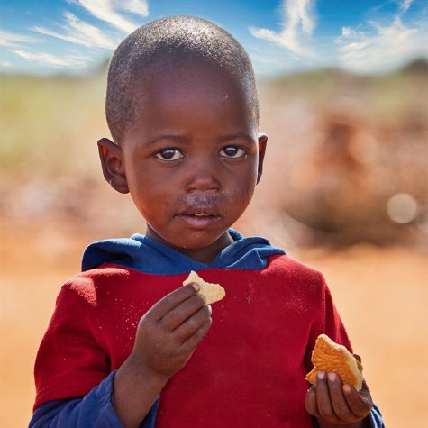 African child  eating biscuits in the yard in a village in Botswana